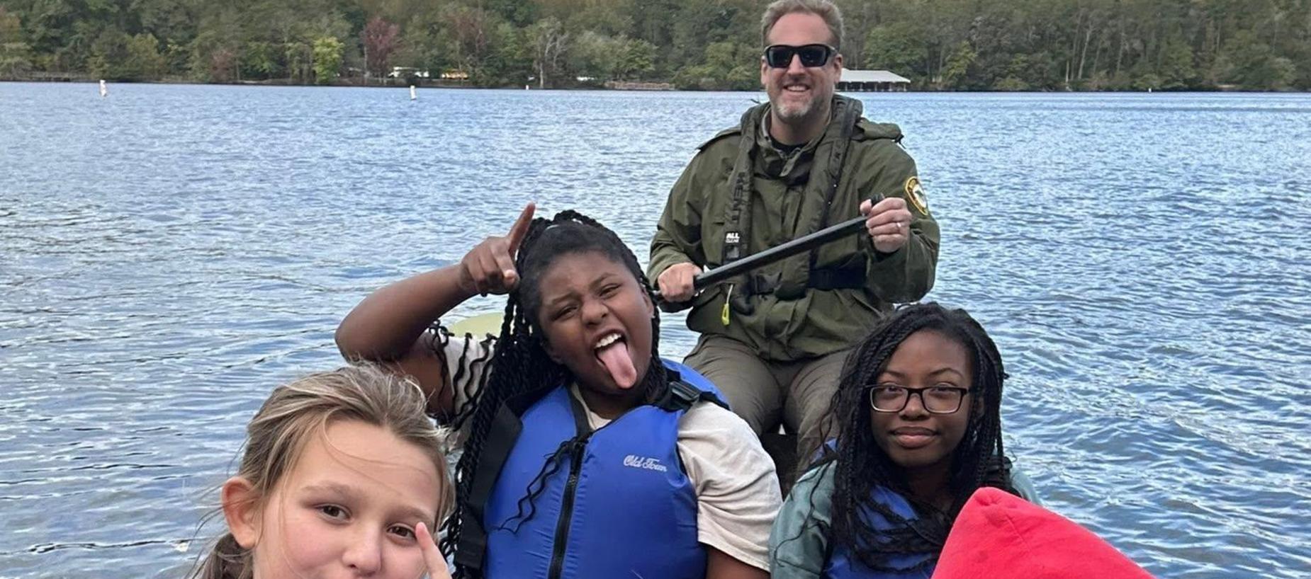 Group of people in life jackets on a boat, posing for a selfie.