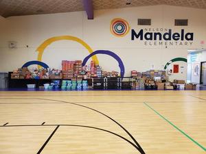 Image shows the Nelson Mandela Elementary gym wall covered in donations for the food drive