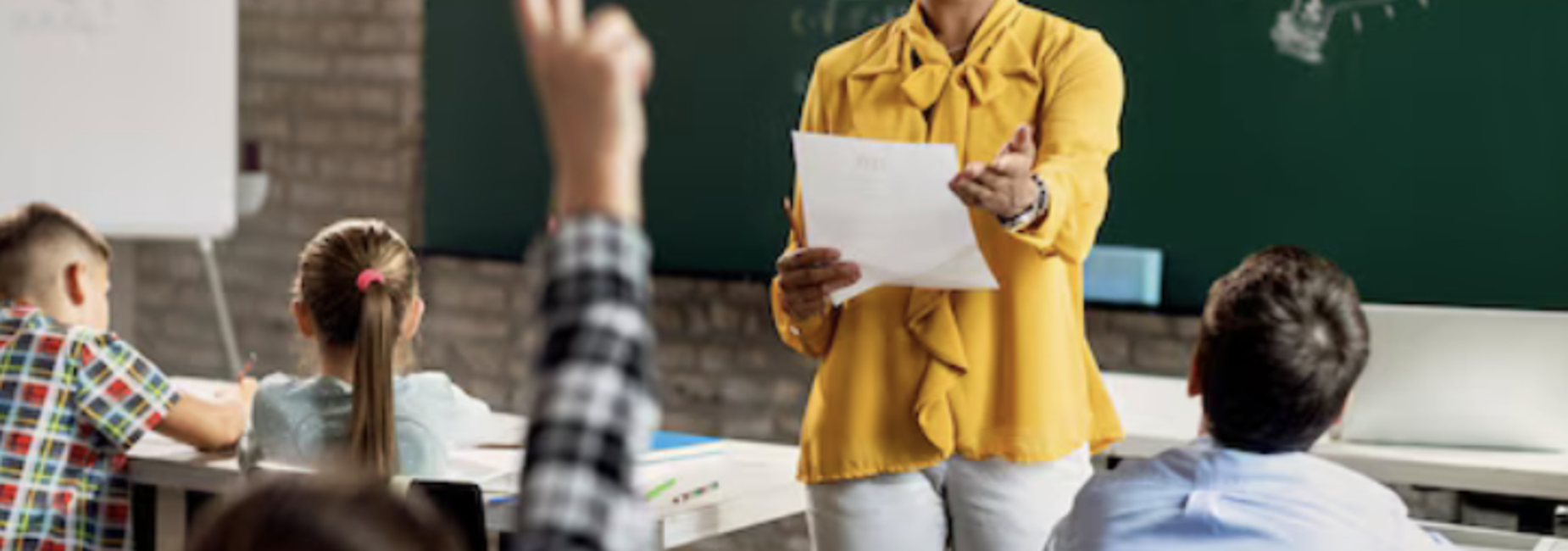 teacher in front of a chalkboard with students in desks