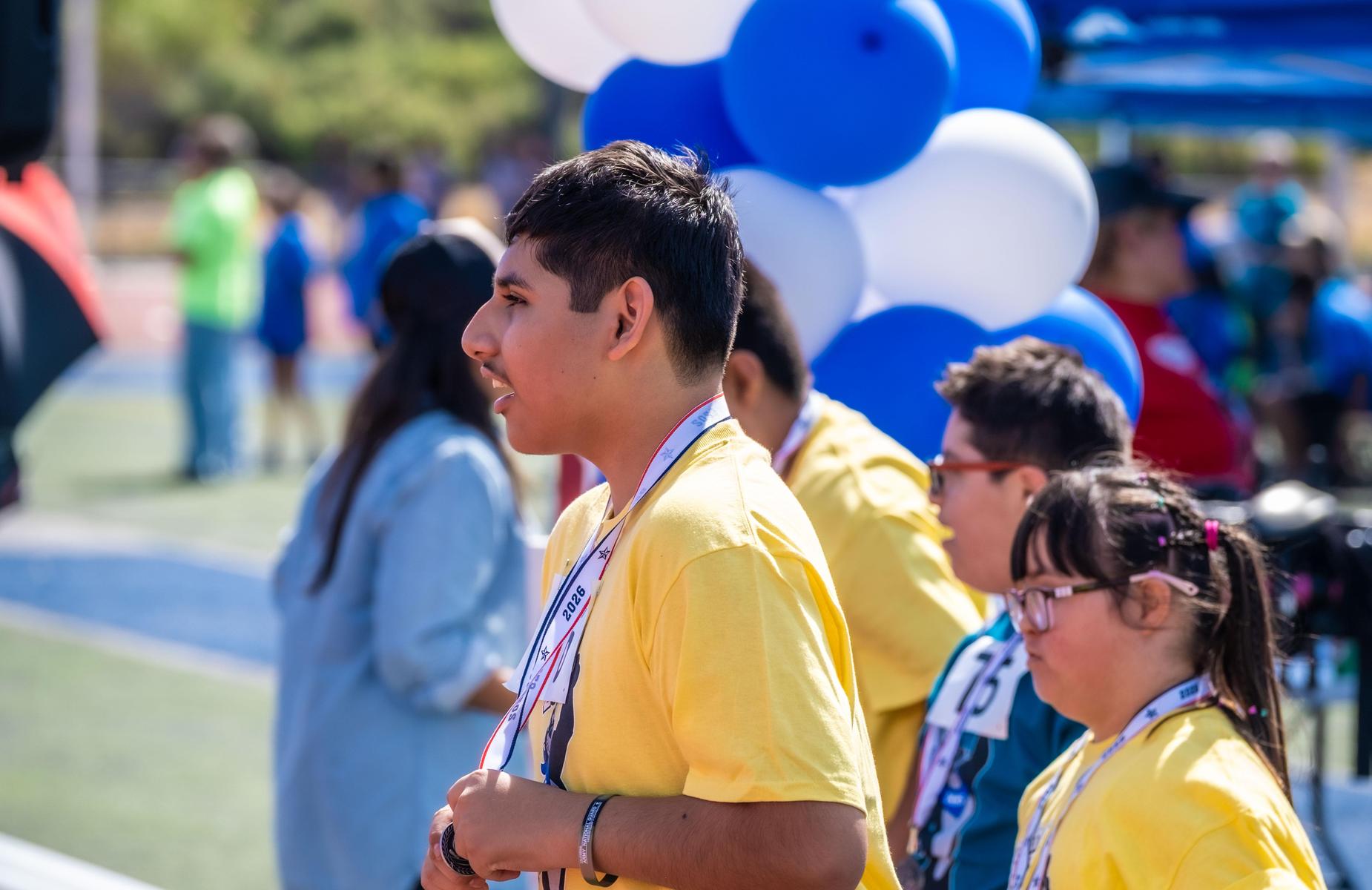 Student holds medal at podium while being cheered for placing 1st