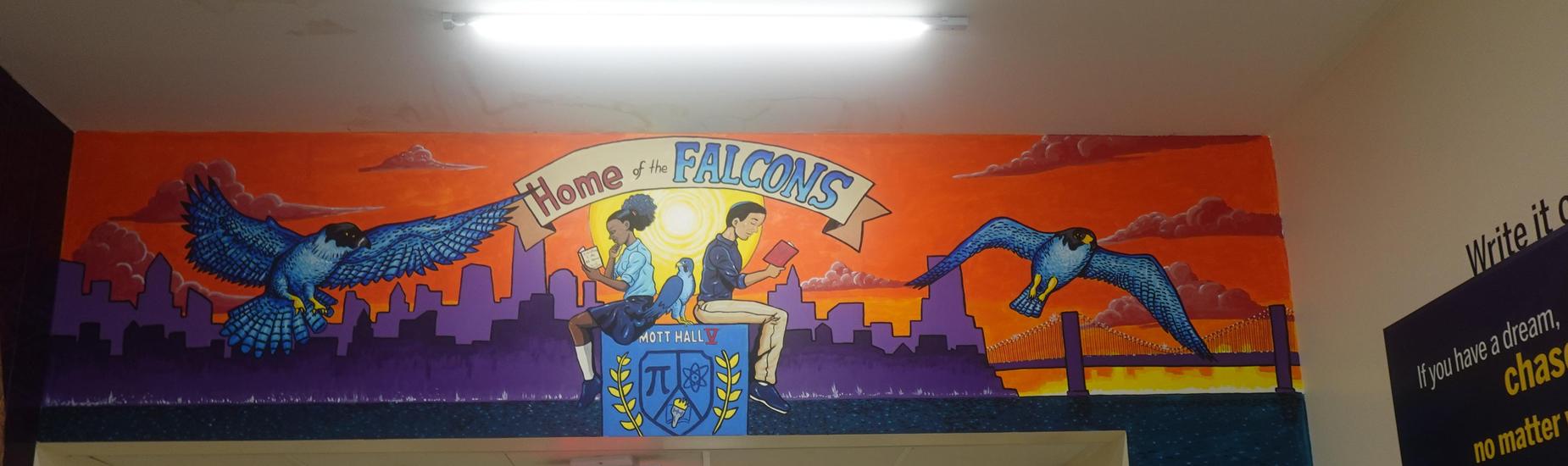 Colorful Mott Hall V mural above the hallway entrance showing two students reading with falcons flying over a sunset city skyline and the banner ‘Home of the Falcons.