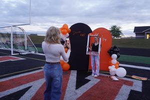 Students take photos on the field of the start of their senior year.