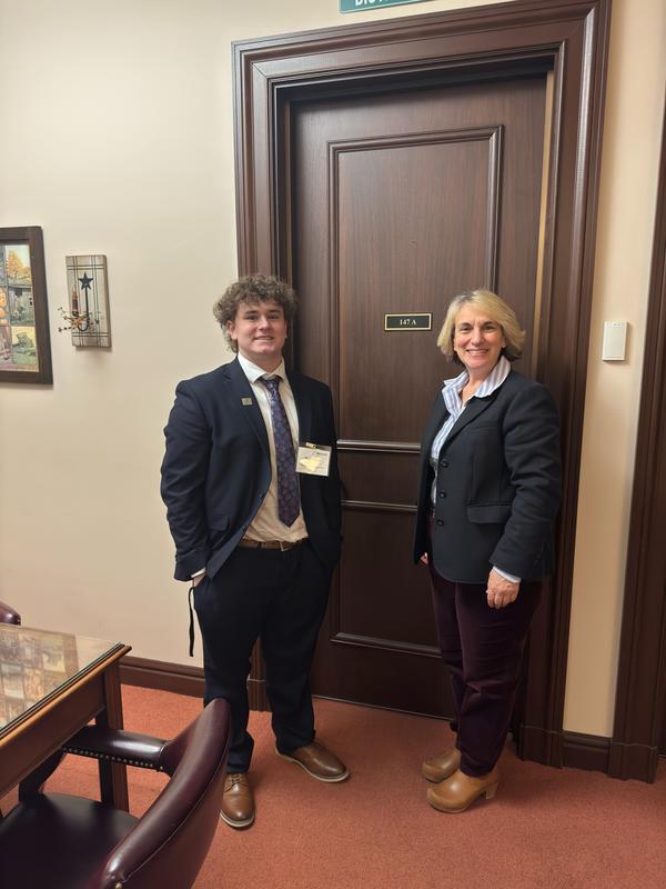student in suit standing with state representative