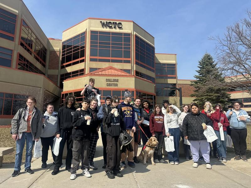 Group of students and a dog posing in front of the WCTC building.