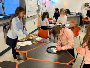 second grade girls making fruit salad.