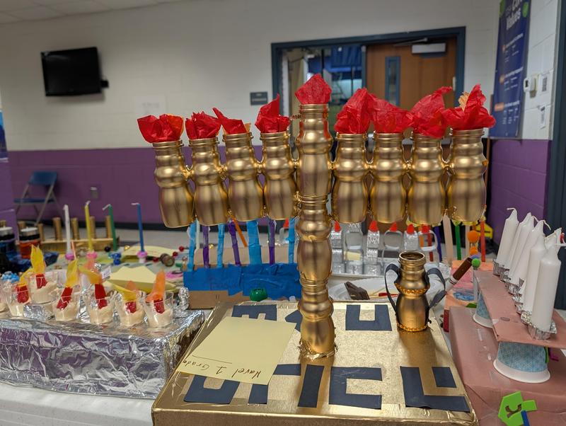 A gold menorah made from used yogurt cartons.