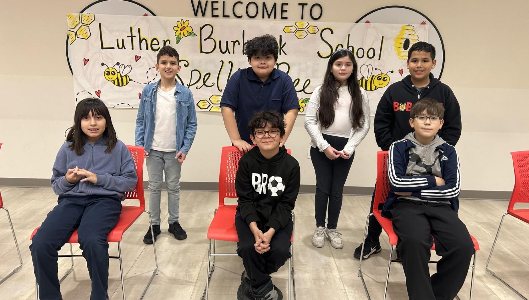Group of six students sitting in chairs smiling in front of a welcome banner.