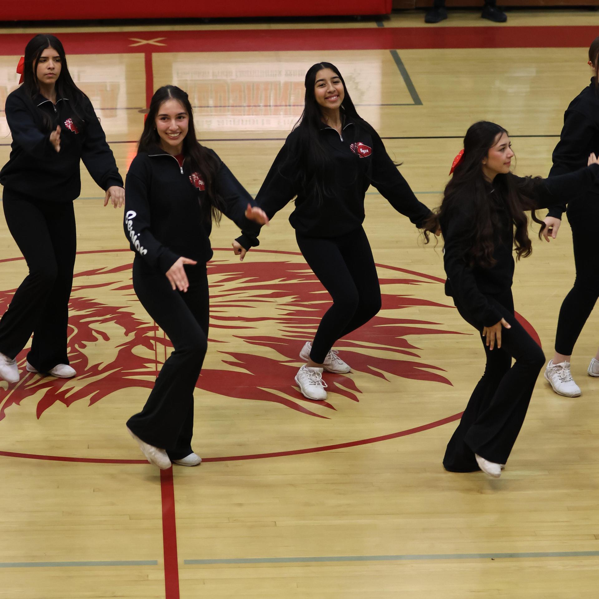Varsity girls cheering at a basketball game against Mariposa