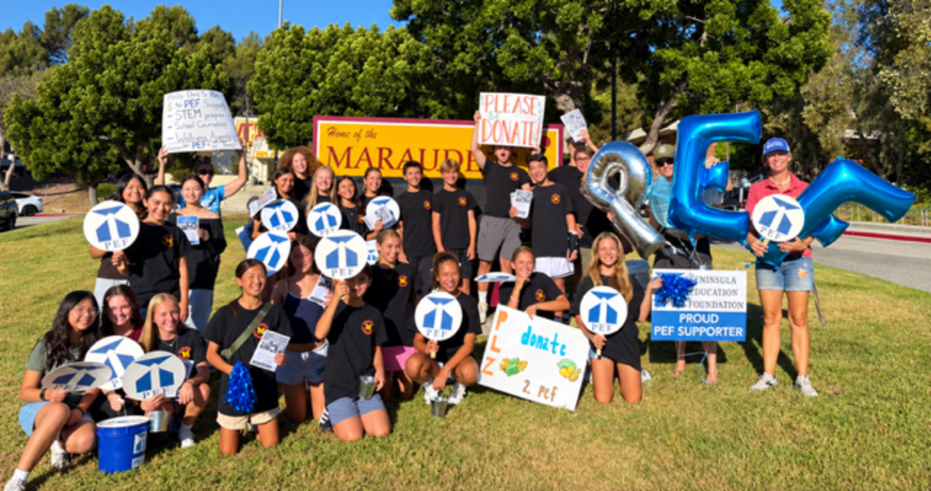 A group of students holding signs and balloons at a fundraising event outside.