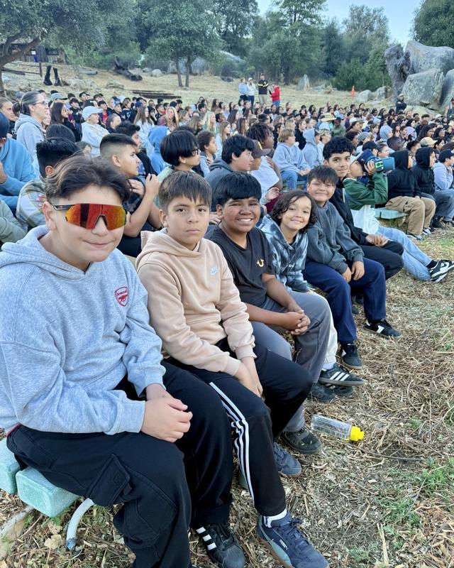 Students sit together outside for a presentation