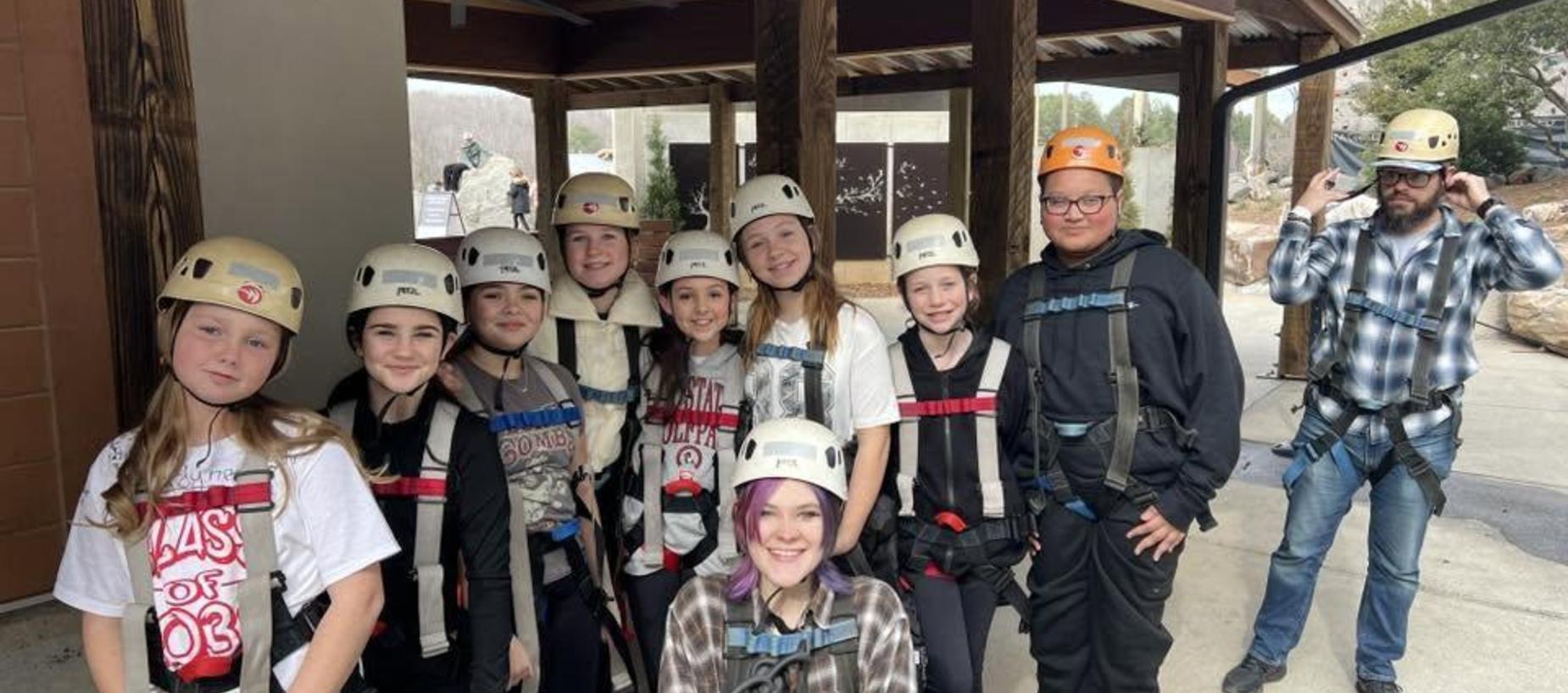 A group of students in safety gear, preparing for an outdoor activity.