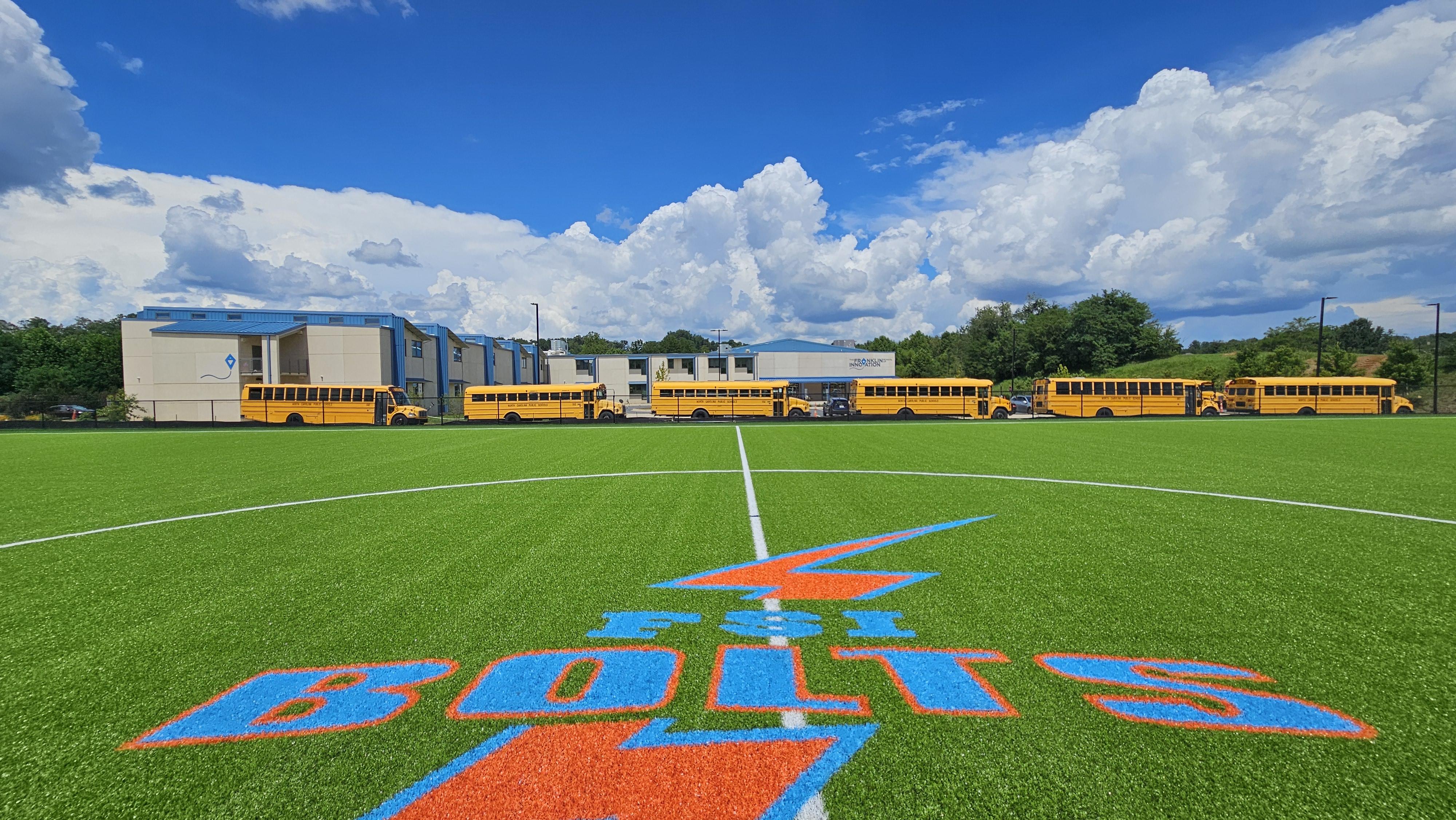 Turf field with the school logo in the foreground and building in the background