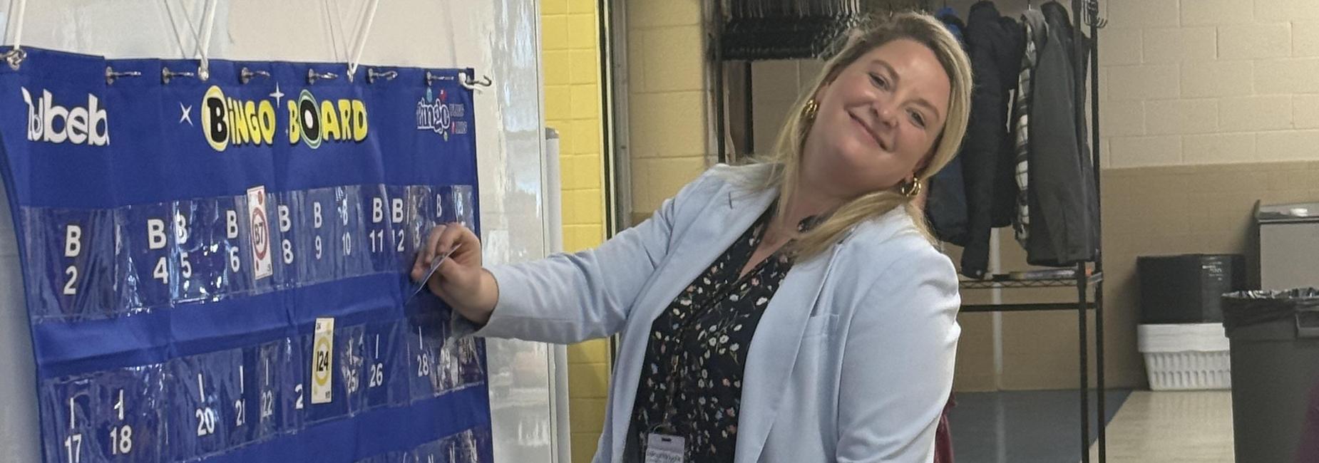 A woman marking a bingo card on a blue board in an indoor setting.