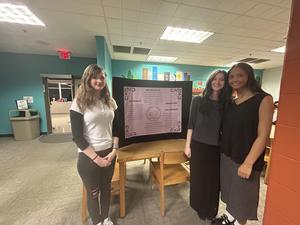 Smiling students stand with school projects