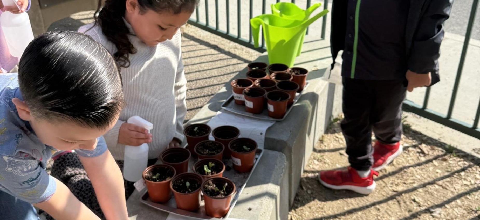 Children planting in pots outdoors near a watering can.