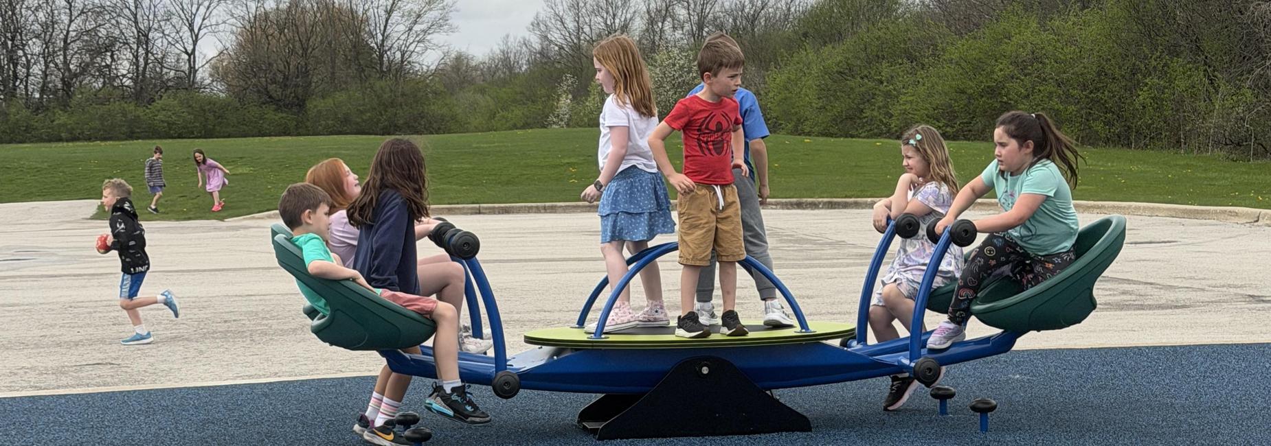 Children playing on a colorful playground see-saw with a rubber surface.