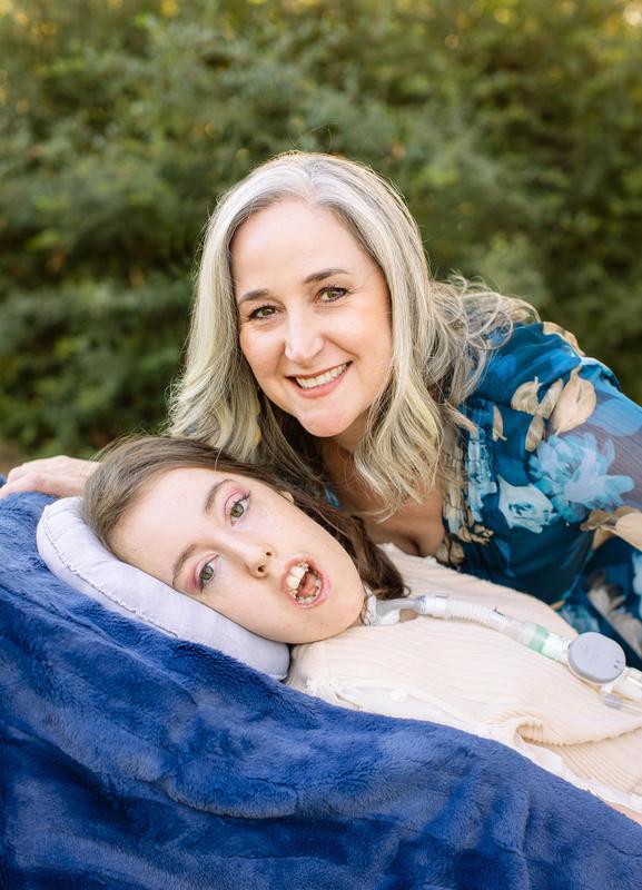 Jennifer Swan smiles with Kennedy Swan. Kennedy is lying against a blue blanket