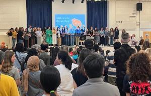 Crowded Multipurpose Room with teachers on stage.