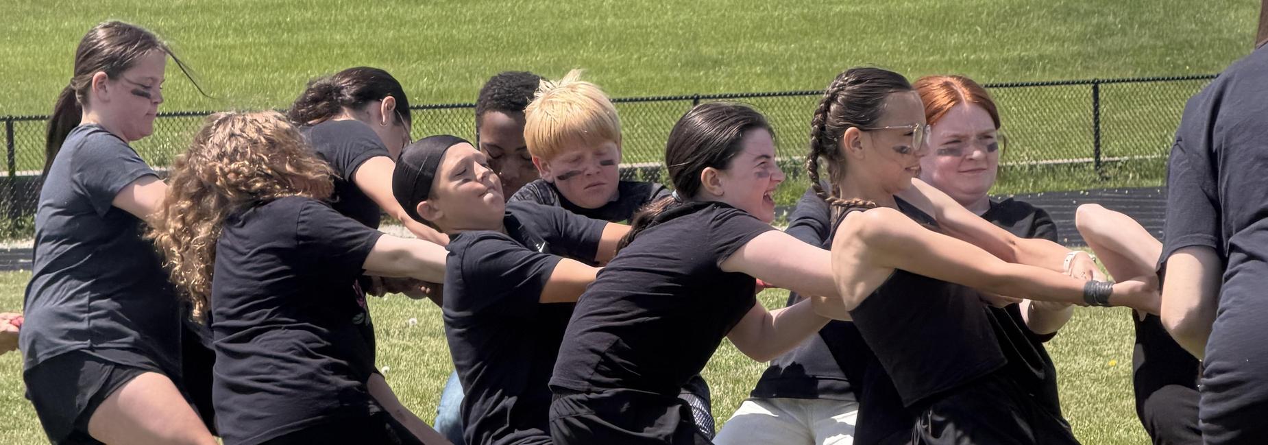 Close-up of legs from participants in a tug-of-war on grass.
