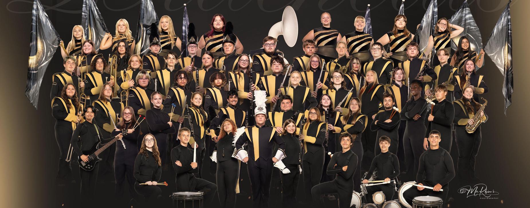 Large band with members in uniforms posing together with instruments.