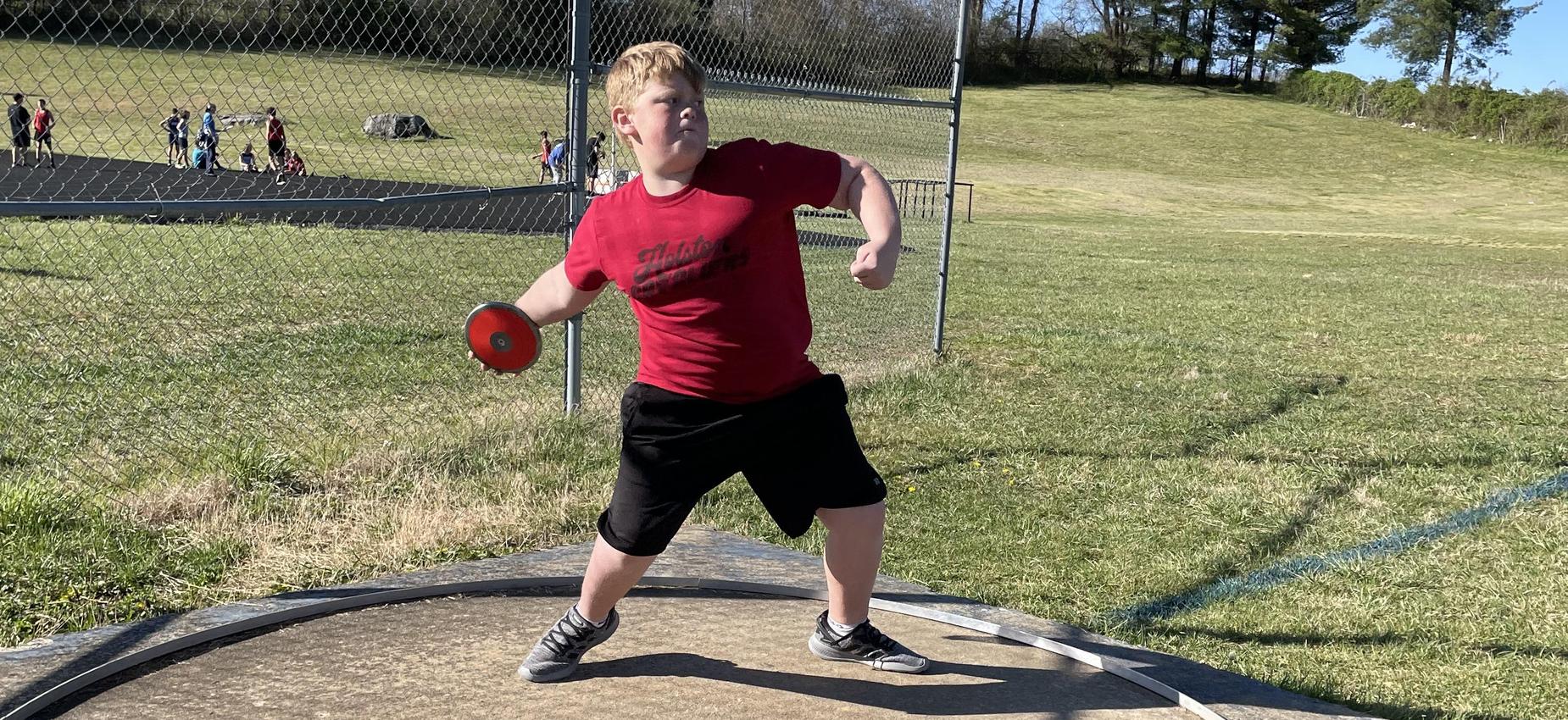A boy throws a discus.