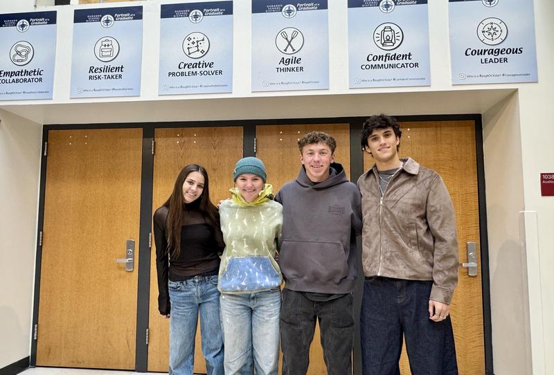 Four Durango High School students stand in front of Portrait of a Graduate posters