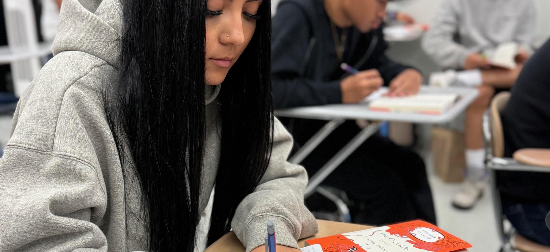 Student reading and writing at a desk
