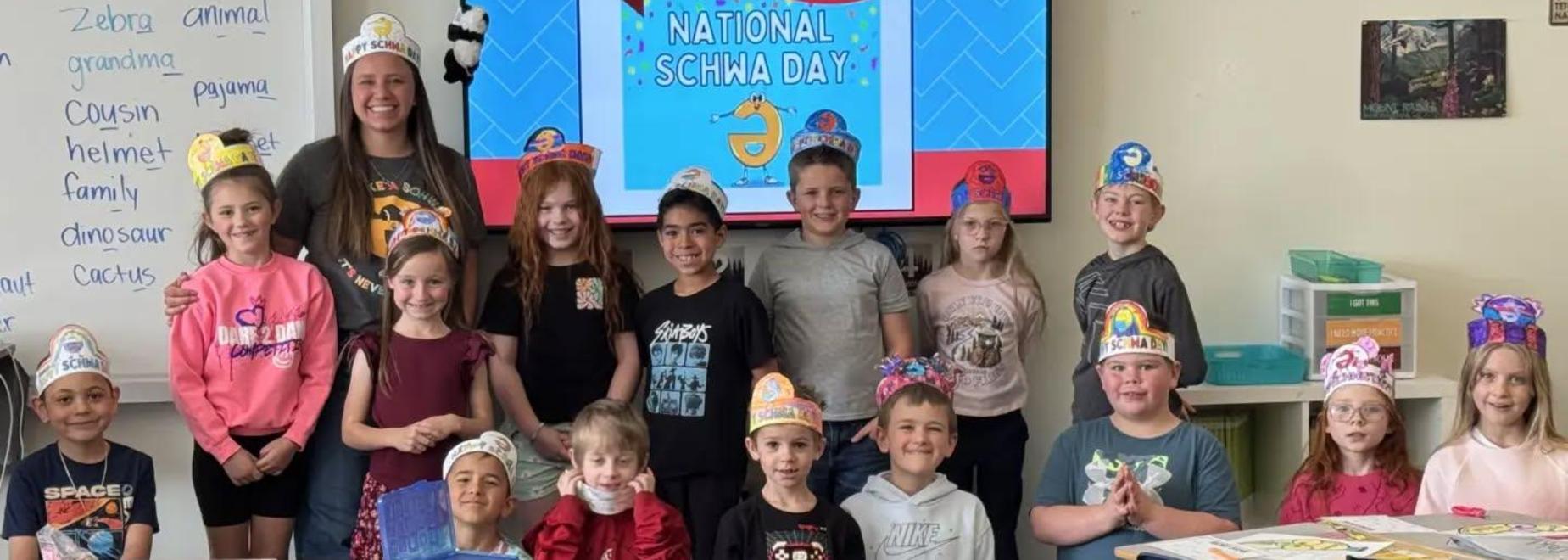 A classroom full of students wearing colorful hats, smiling and posing for a group photo.