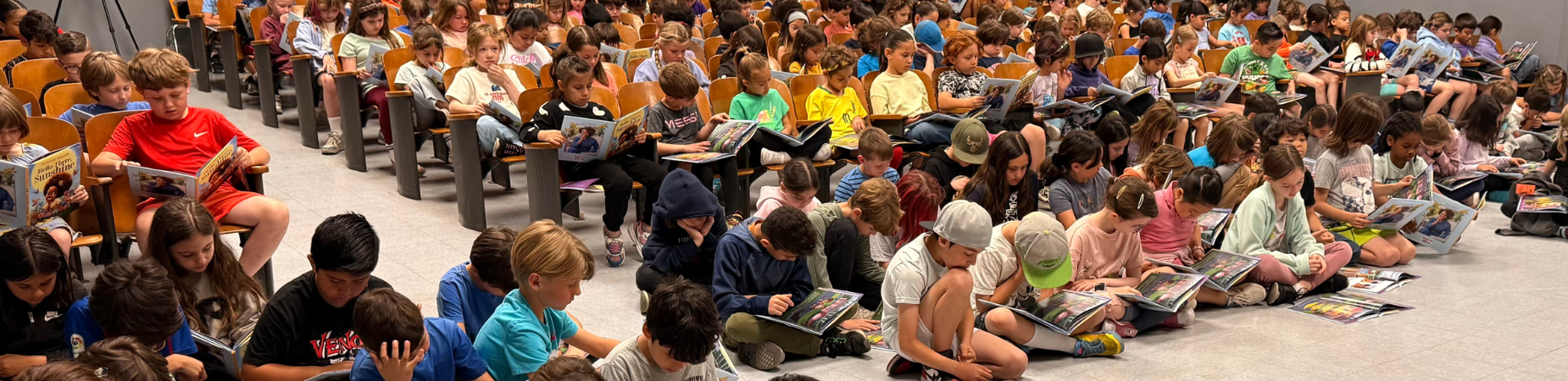 Students reading in an assembly.