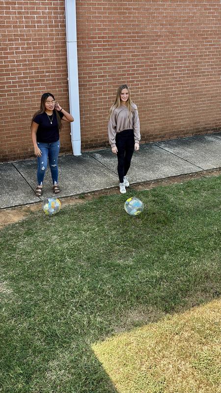 Two girls think about their strategy of kicking the ball up the hill