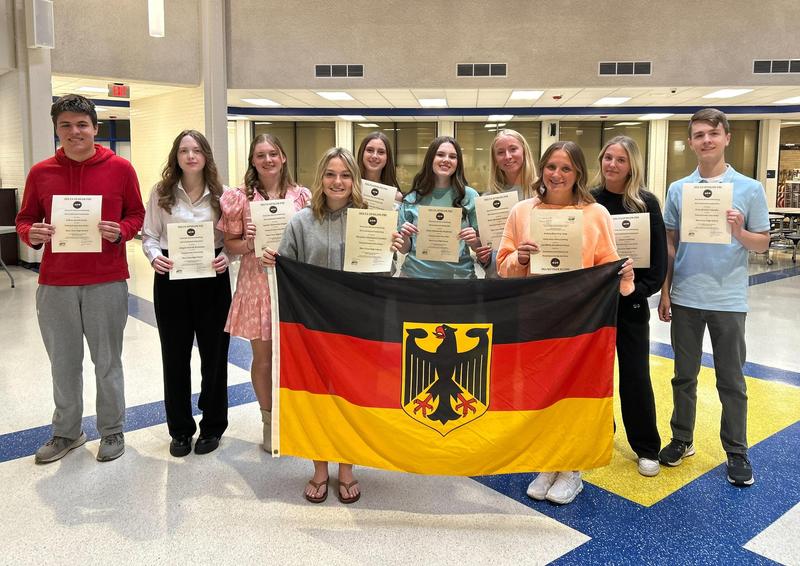 A group of students holding certificates and posing with the German flag