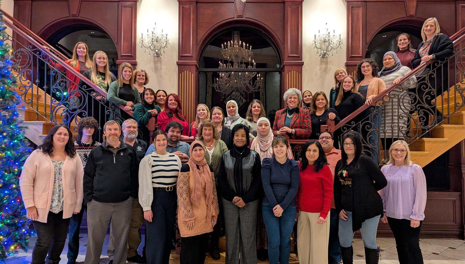 A large group of people gathered on a grand staircase decorated for the holidays.
