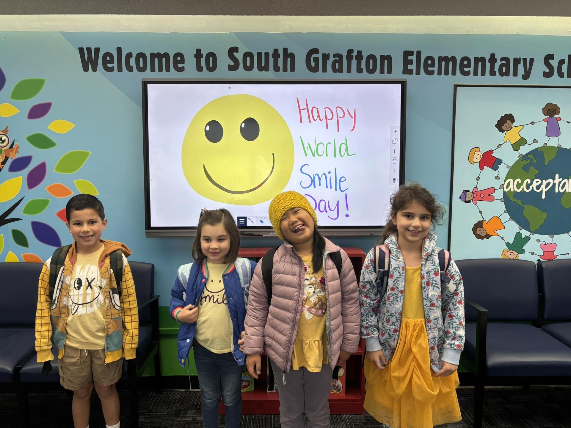 students smiling and showing their smiley face shirts for smile day