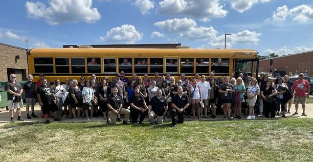 school bus with adults posing in front