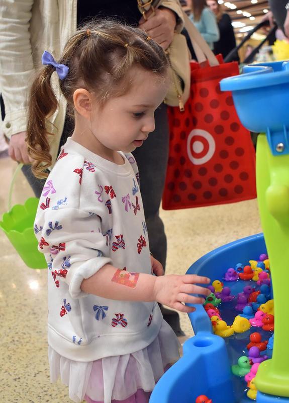 Girl interacts with a game featuring floating rubber ducks in a play area.