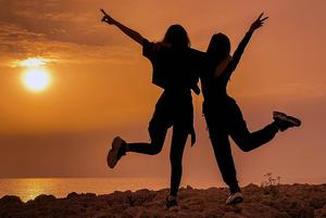 Two dancing teenagers silhouetted by a sunset