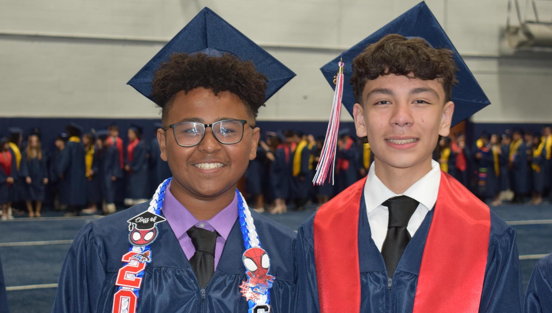 Two male graduates smiling together at a graduation ceremony.