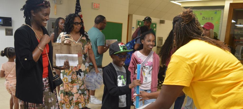 Assistant Principal hands popsicles to two students.