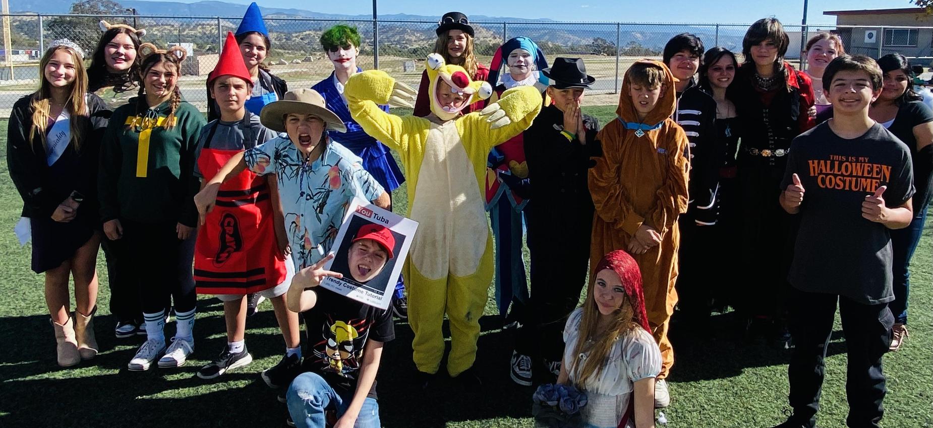 Group of people in costumes celebrating Halloween in a sunny outdoor setting.