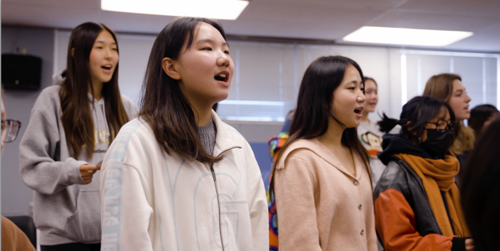 Students singing together in a classroom, showing engagement and teamwork.