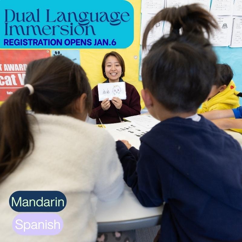 A smiling teacher holding a Mandarin language flash card