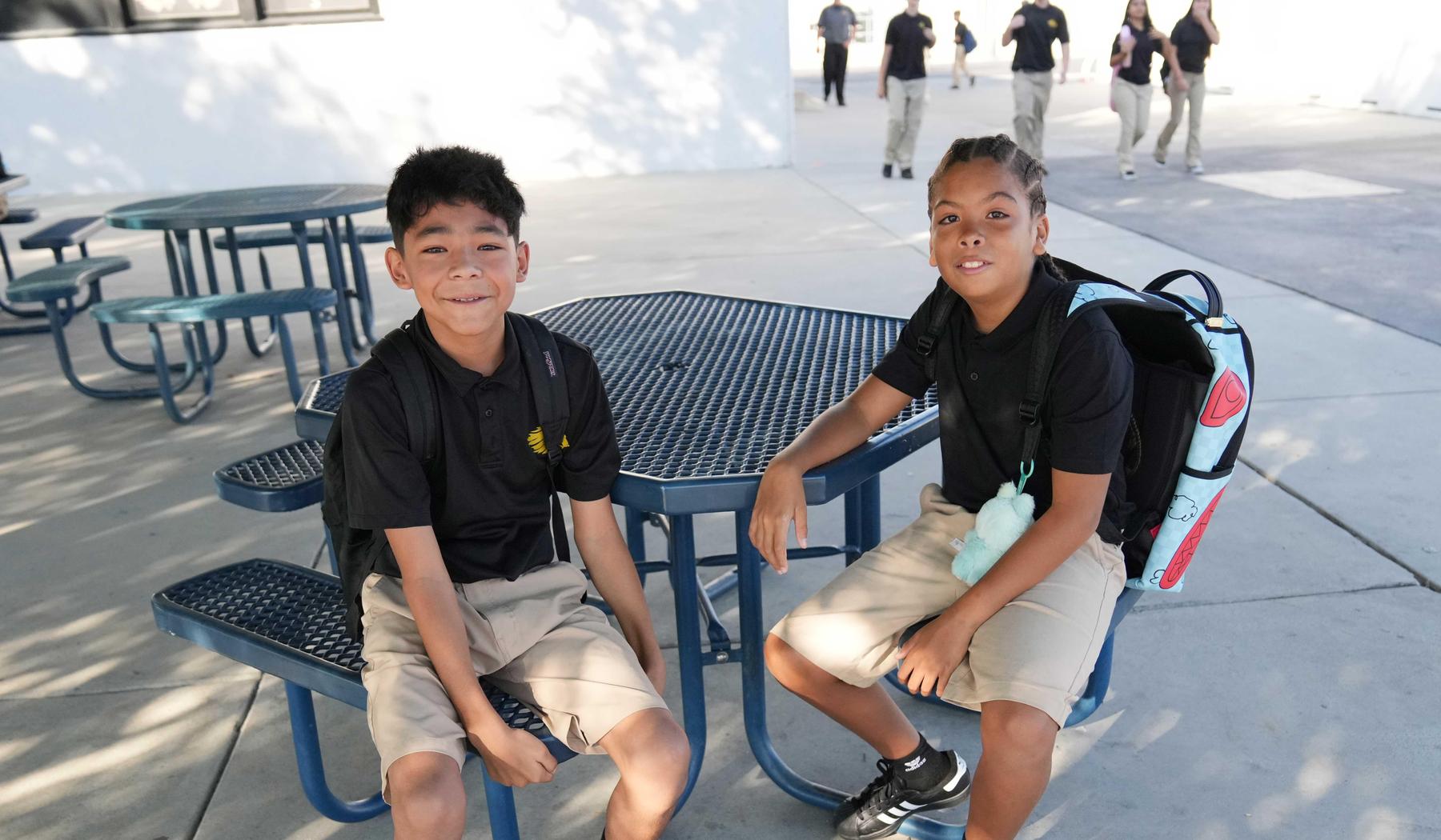 two boys sitting at outside picnic table at school
