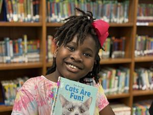 girl elementary student smiles with book
