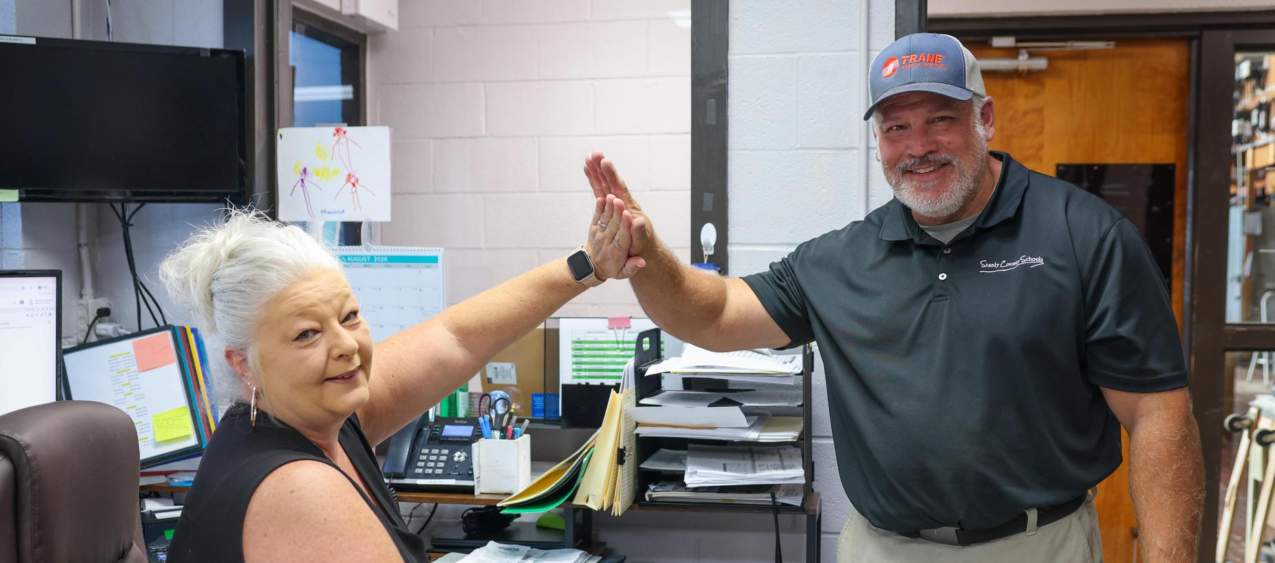 Two people giving a high-five in an office setting.