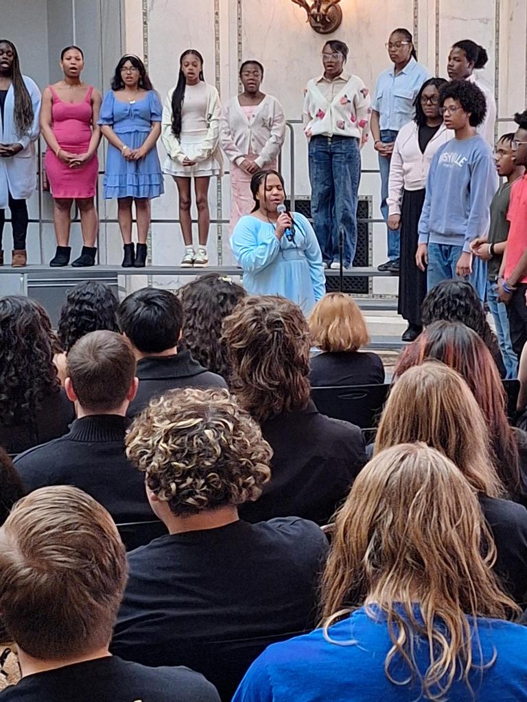 Choir singing in front of seated crowd.