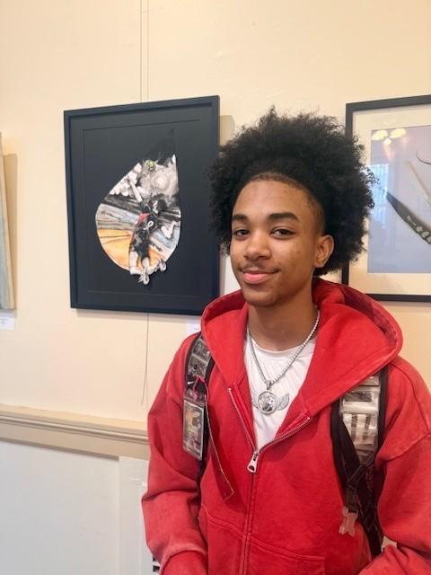 Student in front of their framed artwork on the wall