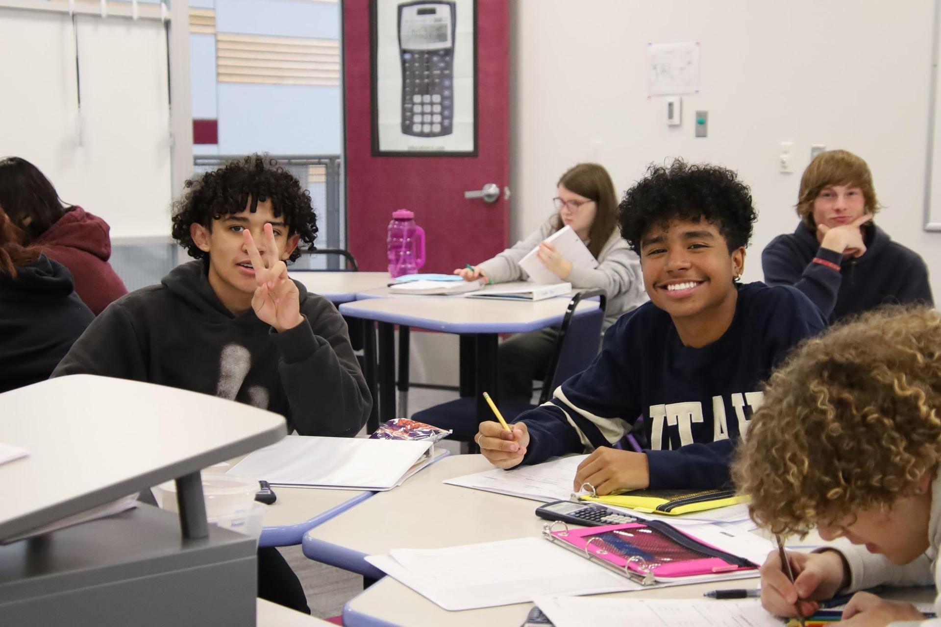 two high school boys smiling for the camera in a classroom