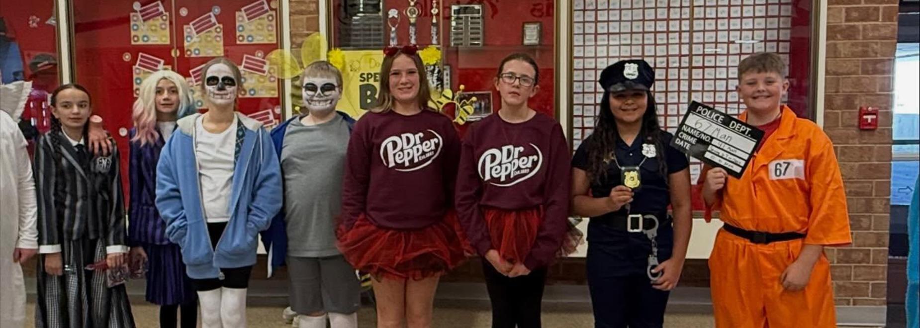 Group of children in costumes including a police officer and a ghost, posing for the camera.