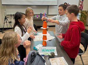 Children collaboratively stacking plastic cups during a group activity.