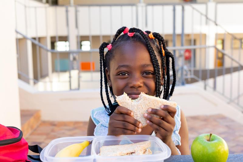 Young girl eats sandwich while facing camera